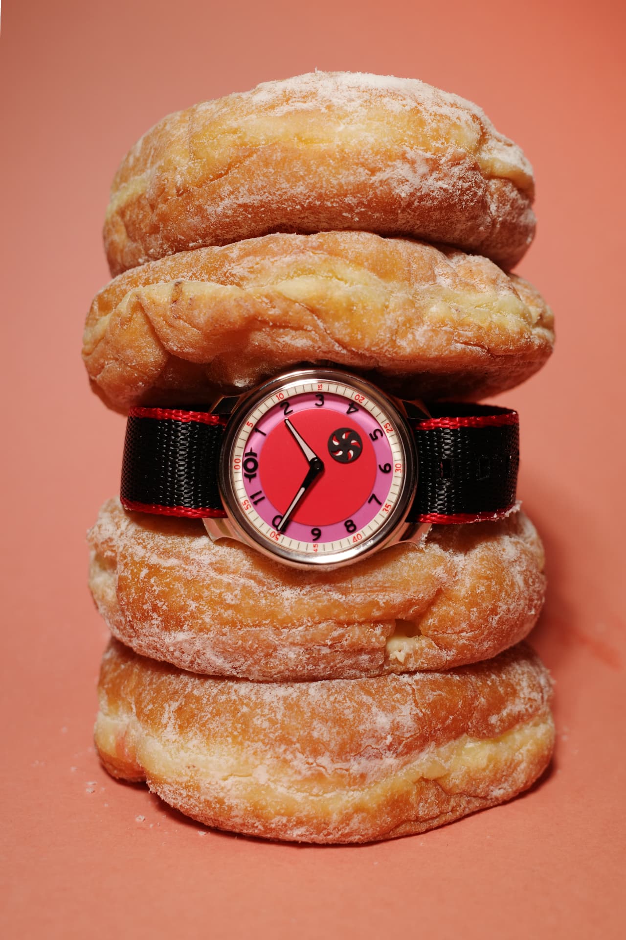 Donut Watch Co. Jelly Donut displayed on a stack of powdered doughnuts