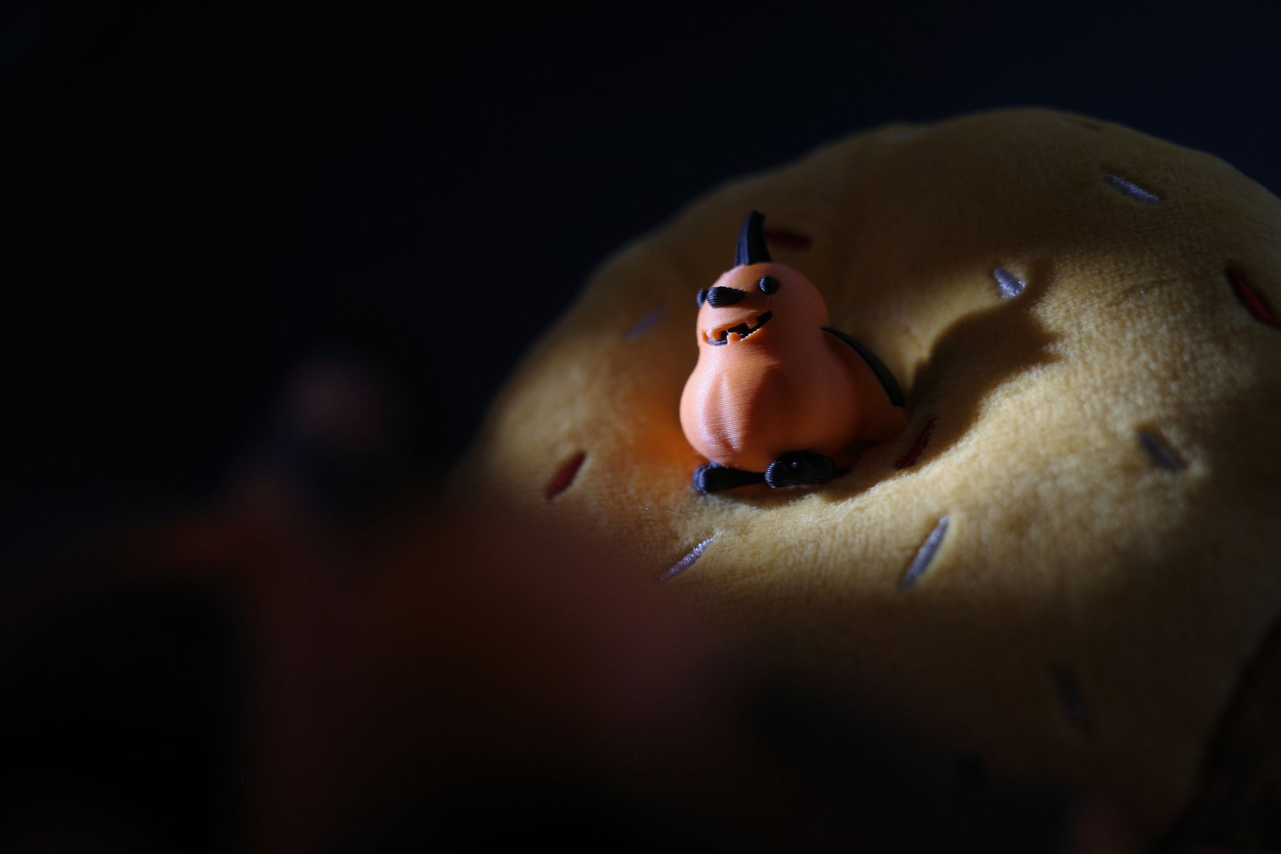 Snowball, the pumpkin-bird figure, resting on a plush donut